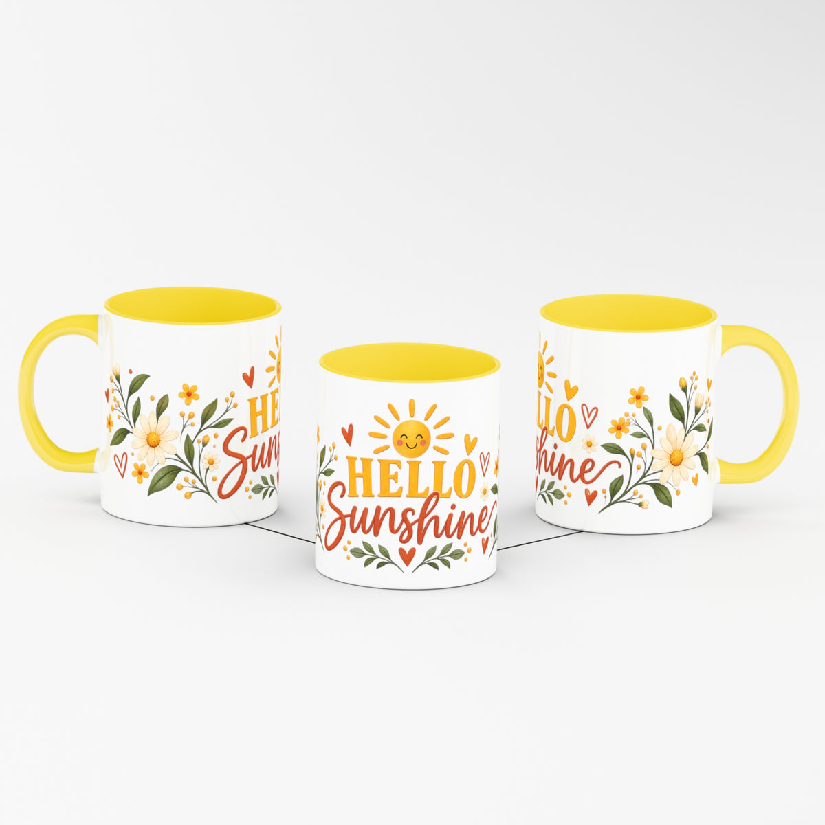 Three white ceramic mugs with yellow interiors and handles, arranged in a row on a light gray background. Each mug features a floral design with yellow sunflowers, green leaves, and red hearts, with the words 'HELLO Sunshine' printed on the front in red and yellow.