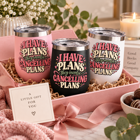 Three insulated tumblers in pink, black, and white are arranged in a pink gift box with shredded paper filler. Each tumbler has the phrase “I HAVE PLANS they involve CANNING PLANS” in stylized lettering.