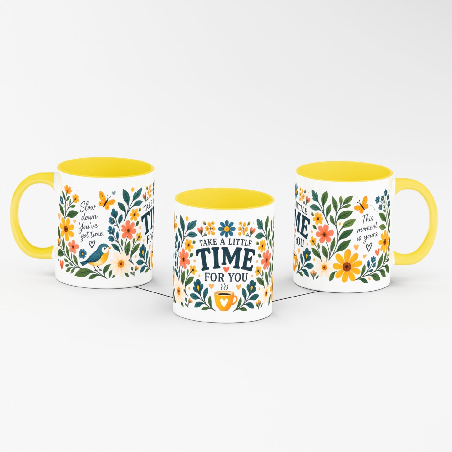 Three white ceramic mugs with yellow interiors and handles, decorated with colorful floral illustrations and the phrase 'TAKE A LITTLE TIME FOR YOU', shown on a clean white background.
