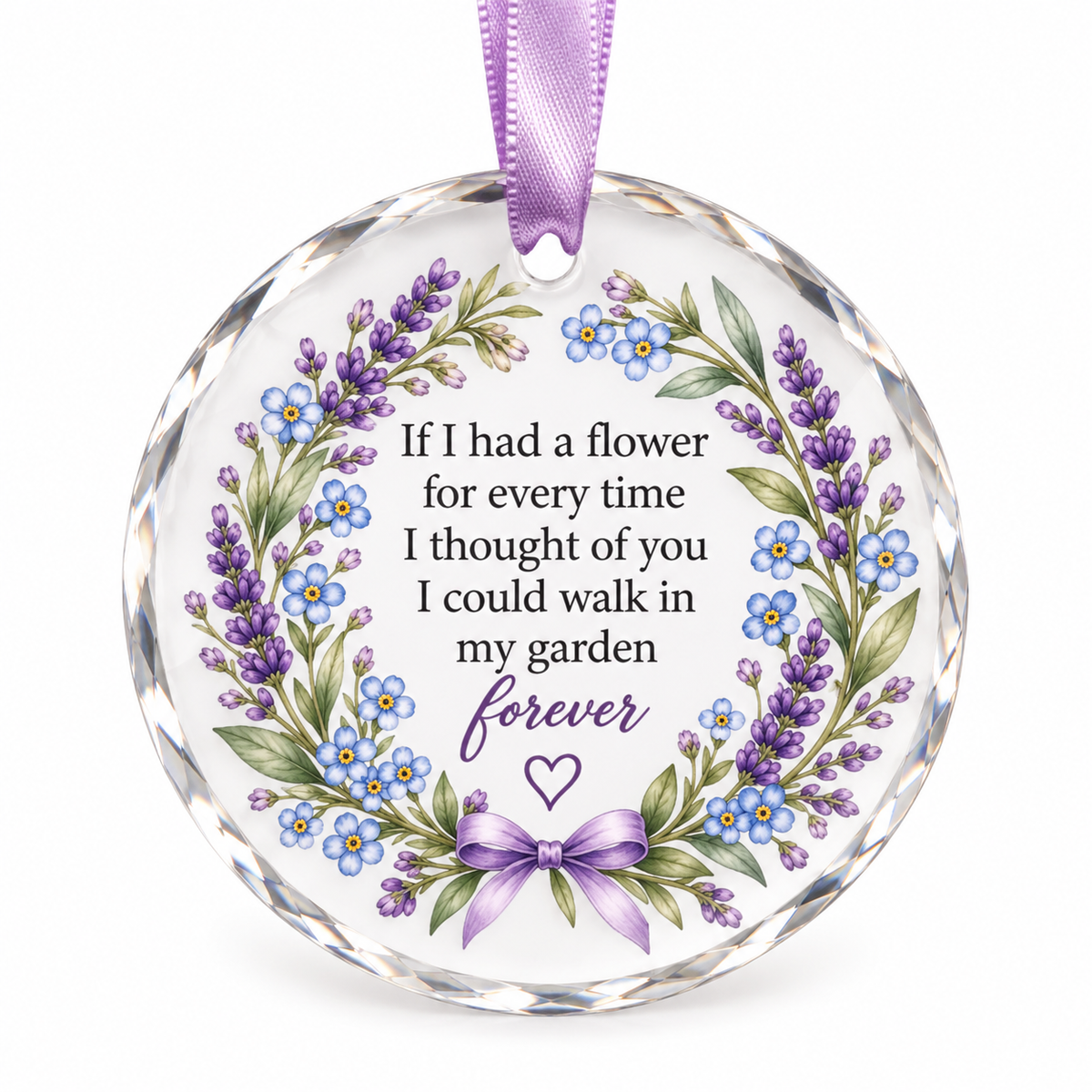Round clear glass or acrylic hanging ornament with a purple ribbon loop, featuring a floral wreath design with purple lavender, blue forget-me-nots, green leaves, and printed memorial text on a white background.